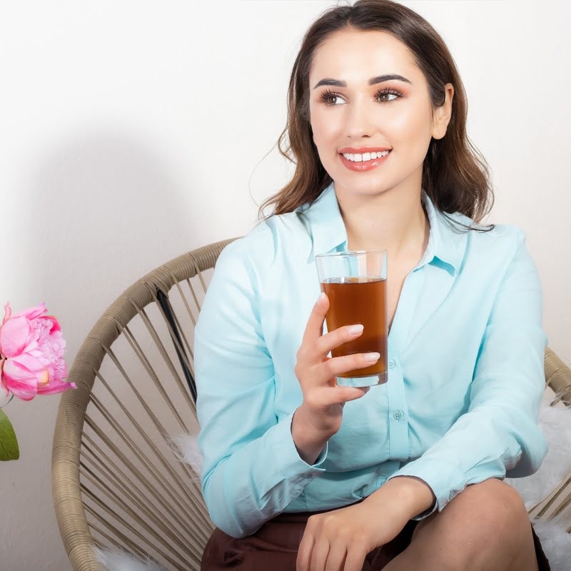 Frau hält ein Glas Wasser mit aufgelöstem Shilajit