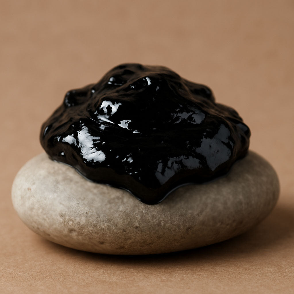Dunkle, glänzende Shilajit-ähnliche Masse auf einem glatten, hellen Naturstein